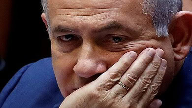 Close-up of Netanyahu covering part of his face, showing concern or distress.