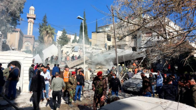أشخاص وقوات أمنية يتجمعون أمام مبنى دمر في غارة إسرائيلية على دمشق في 20 يناير/كانون الثاني 2024
