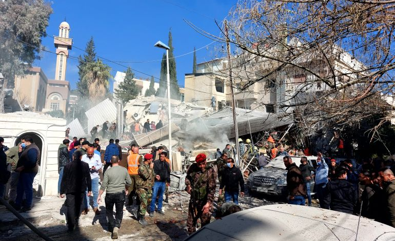 أشخاص وقوات أمنية يتجمعون أمام مبنى دمر في غارة إسرائيلية على دمشق في 20 يناير/كانون الثاني 2024