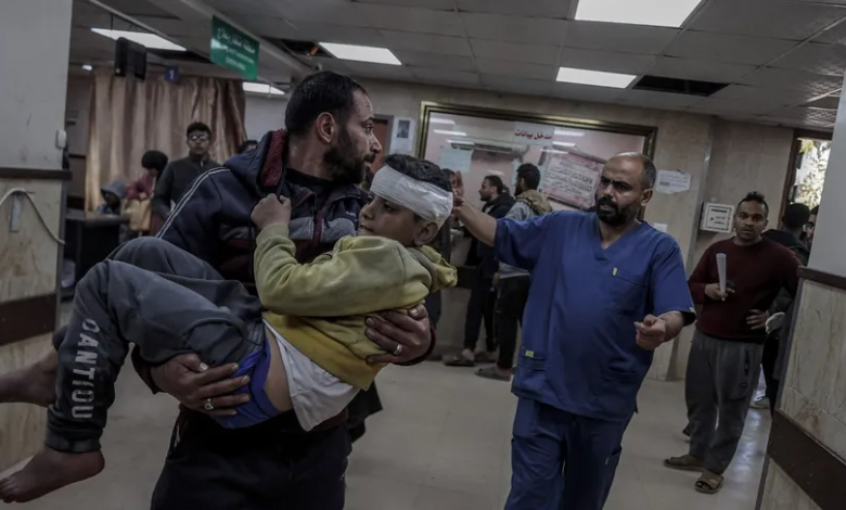 فلسطيني يحمل طفلاً مصاباً في هجمات إسرائيلية على مخيم النصيرات بقطاع غزة. 17 فبراير 2024