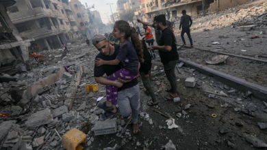 فلسطيني يحمل طفلة لانقاذها من قصف إسرائيلي