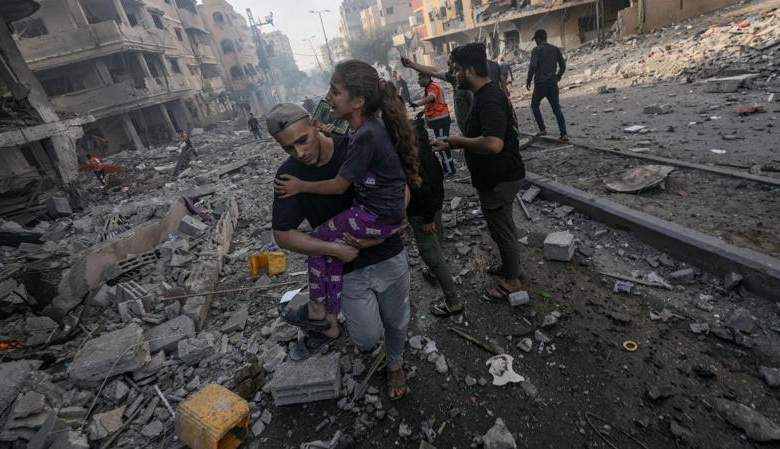 فلسطيني يحمل طفلة لانقاذها من قصف إسرائيلي