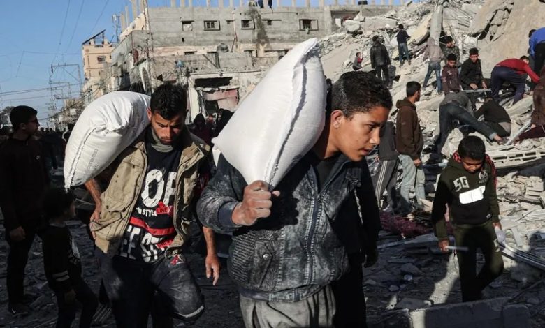 فلسطينيون يحملون بعض المساعدات بينما يتفقد آخرون أحد المنازل المدمرة جراء قصف إسرائيلي على رفح للبحث عن ناجين أو مصابين بين الأنقاض. 9 مارس 2024