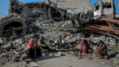 فلسطينيون يجلسون وسط ركام مبنى دمره الجيش الإسرائيلي في قطاع غزة. 26 فبراير 2024