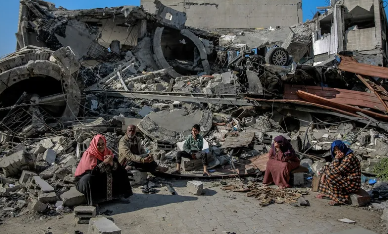 فلسطينيون يجلسون وسط ركام مبنى دمره الجيش الإسرائيلي في قطاع غزة. 26 فبراير 2024