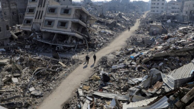 فلسطينيون يسيرون بين أنقاض منازل لحق بها الدمار جراء القصف الإسرائيلي في شمال قطاع غزة يوم 22 فبراير شباط 2024