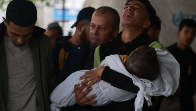 شاب فلسطيني يحمل طفلاً قتلته إسرائيل في قصف على رفح بجنوب قطاع غزة. 29 أبريل 2024